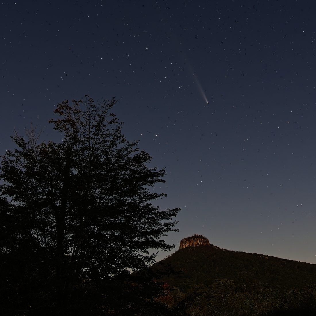 Comet streaking above Pilot Mountain silhouette under a starry twilight sky — Pilot Mountain, NC