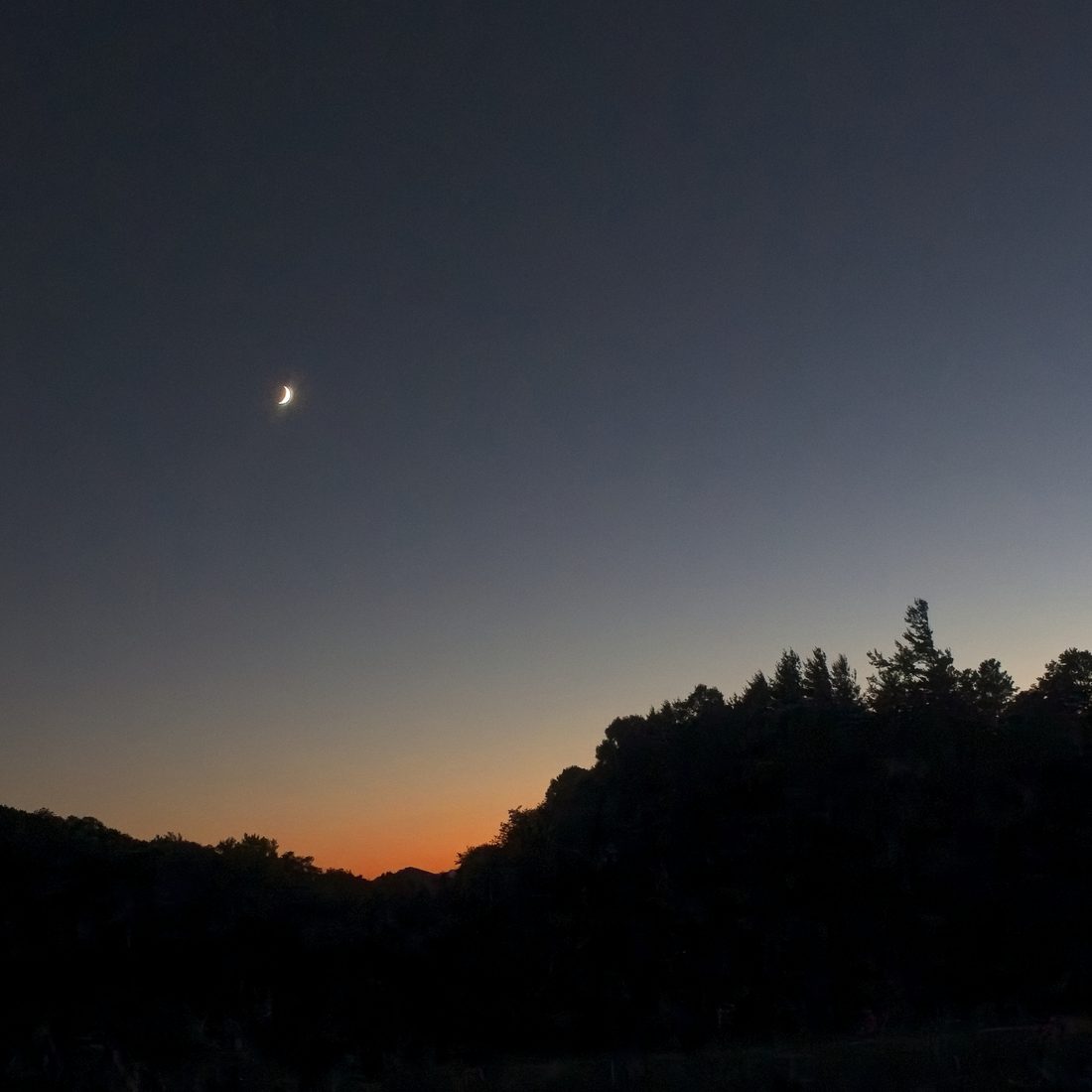 Crescent moon rising above silhouetted ridge at the blue hour — Blue Ridge Parkway