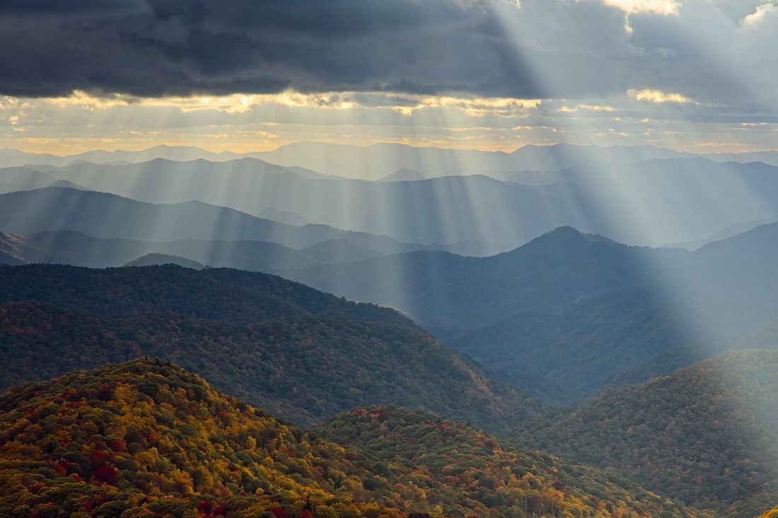 Layered Blue Ridge summits with golden god rays raking across autumn ridges at sunset — Blue Ridge Parkway