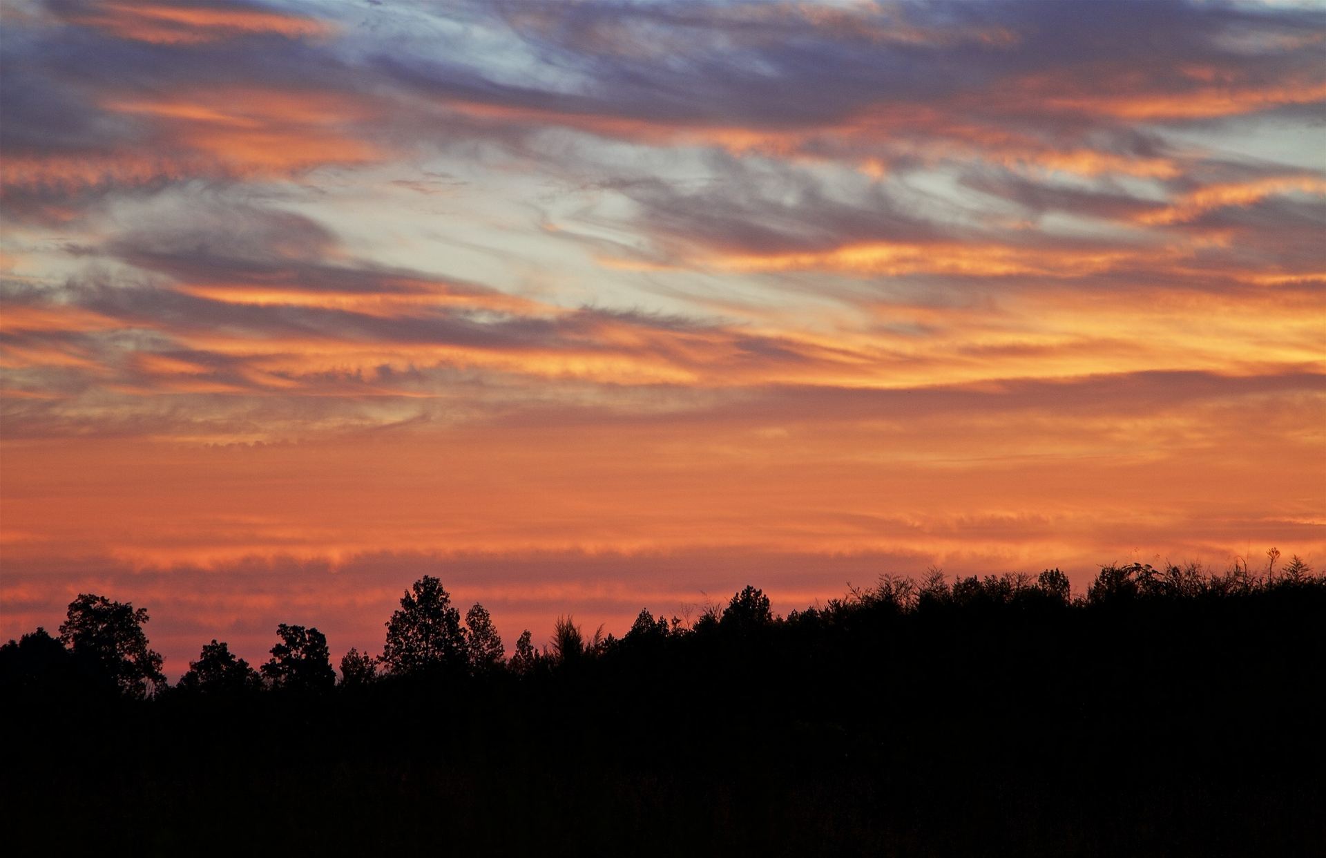 Patterned red cloud bands across a glowing sunset sky over a hazy Blue Ridge valley